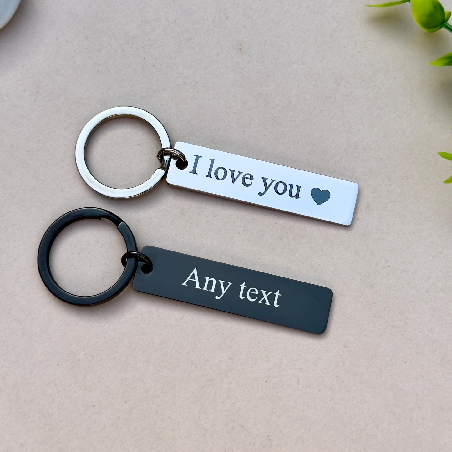 Set of two personalized stainless steel keychains. The silver keychain is engraved with 'I love you' and a heart symbol, perfect for expressing affection. The black keychain features customizable text, allowing you to add a personalized message or special date. Both keychains are made from durable stainless steel, attached to strong metal rings, making them ideal as gifts for loved ones, anniversaries, or as thoughtful keepsakes